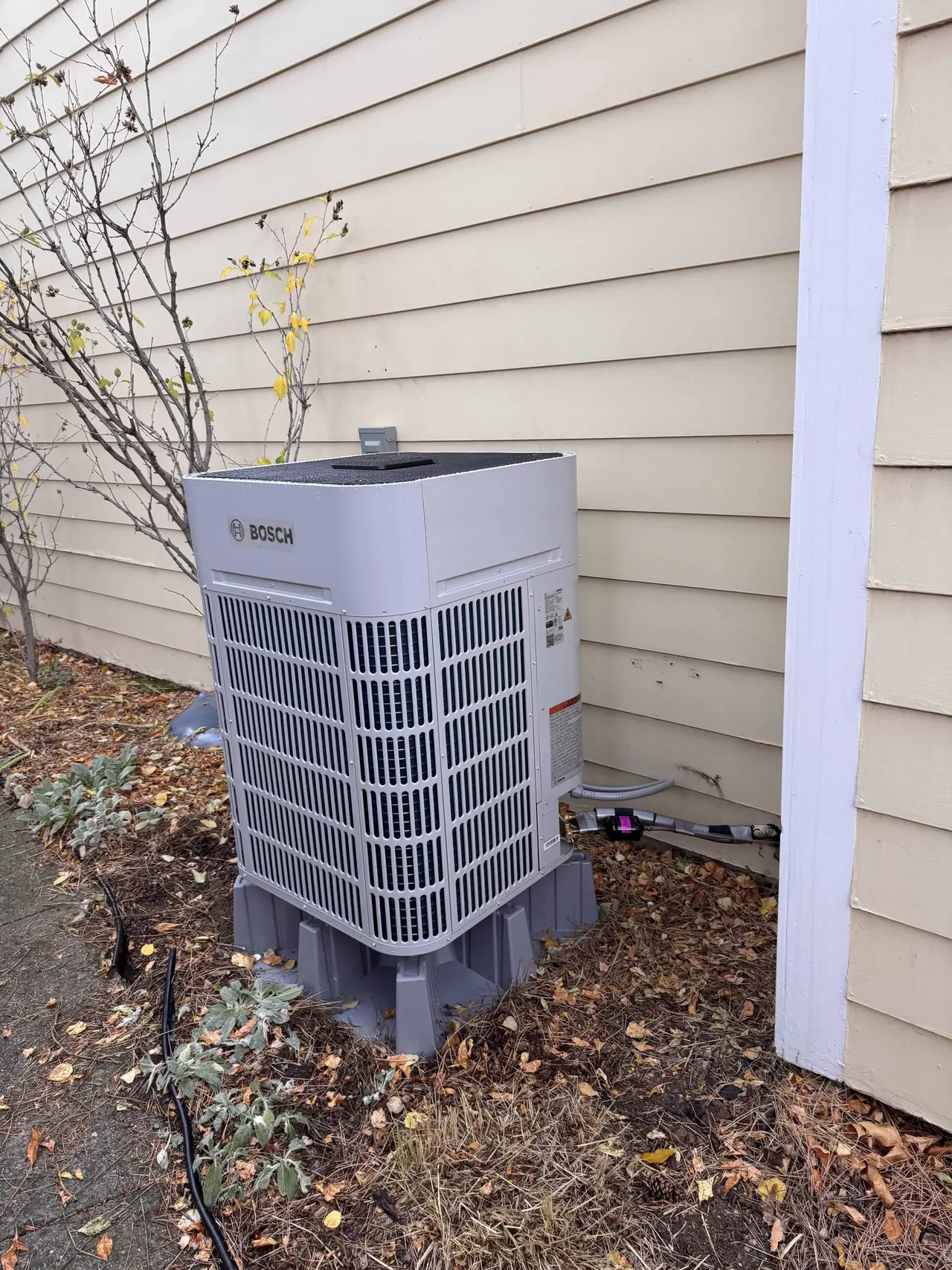 Heat pump outdoor unit on a concrete pad beside a Denver home