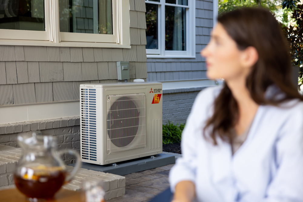 Homeowner on a patio next to a Mitsubishi mini split outdoor unit